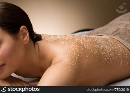wellness, beauty and relaxation concept - close up of beautiful young woman with sea salt on skin at spa. close up of woman with sea salt on skin at spa