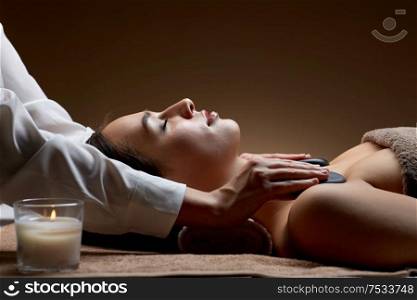 wellness, beauty and relaxation concept - close up of young woman having hot stone massage at spa salon. close up of woman having hot stone massage at spa