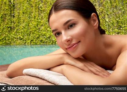 wellness, beauty and relaxation concept - close up of young woman lying at spa over swimming pool at exotic resort in thailand on background. close up of woman lying at spa over exotic resort