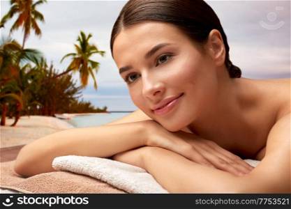wellness, beauty and relaxation concept - close up of young woman lying at spa or massage parlor over tropical beach background in french polynesia. close up of young woman lying at spa