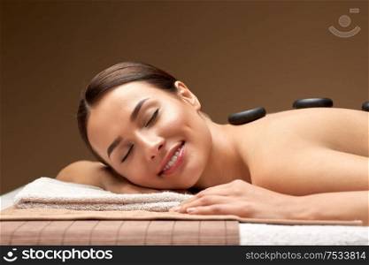 wellness, beauty and relaxation concept - smiling beautiful young woman having hot stone massage at spa. smiling woman having hot stone massage at spa