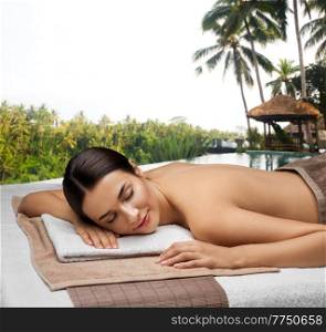 wellness, beauty and relaxation concept - young woman lying at spa over bungalow at exotic resort in thailand on background. young woman lying at spa over exotic resort