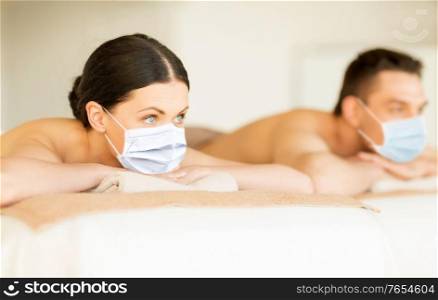 wellness, bodycare and health concept - couple wearing face protective medical masks for protection from virus disease at spa. couple in masks at spa