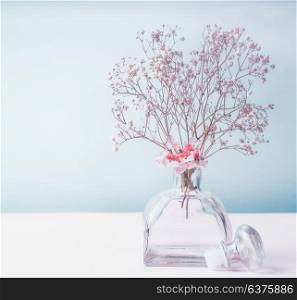 Wellness or aromatherapy concept. Glass jar diffuser with flowers at pastel color background, top view. Aromatic spa set