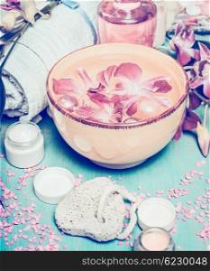Wellness or spa setting with water bowl with flowers, cream, towel and bath tools. Pastel color toned.