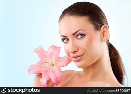 wellness portrait of young woman with pink lily looking in camera with a smile
