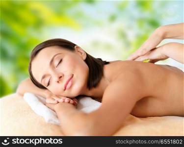 wellness, spa and beauty concept - close up of beautiful woman having massage over green natural background. close up of beautiful woman having massage at spa. close up of beautiful woman having massage at spa