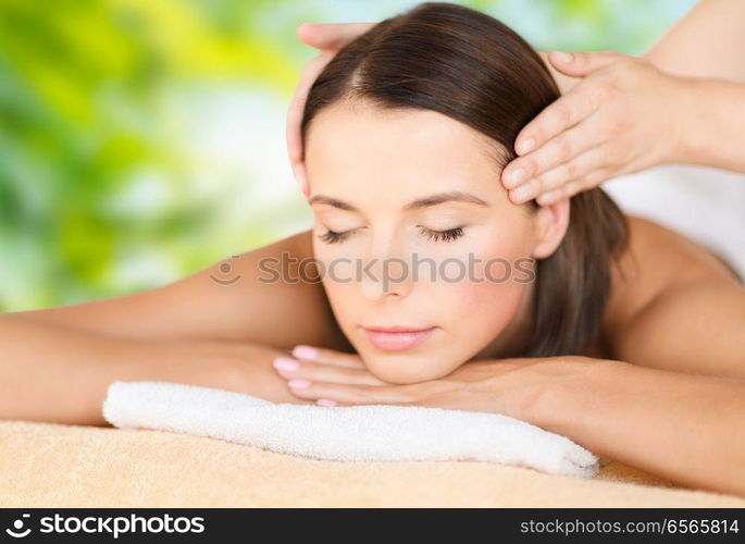 wellness, spa and beauty concept - close up of beautiful woman having head massage over green natural background. close up of beautiful woman having head massage