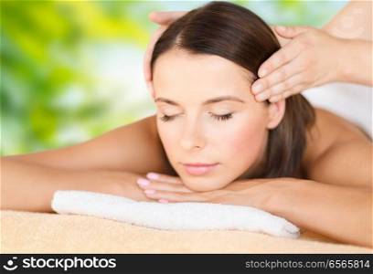 wellness, spa and beauty concept - close up of beautiful woman having head massage over green natural background. close up of beautiful woman having head massage