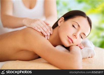 wellness, spa and beauty concept - close up of beautiful woman having massage over green natural background. close up of beautiful woman having massage at spa