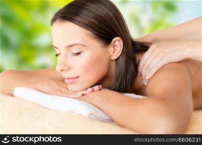 wellness, spa and beauty concept - close up of beautiful woman having massage over green natural background. close up of beautiful woman having massage at spa