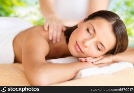 wellness, spa and beauty concept - close up of beautiful woman having massage over green natural background. close up of beautiful woman having massage at spa. close up of beautiful woman having massage at spa