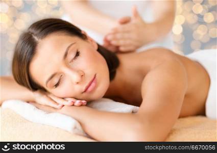 wellness, spa and beauty concept - close up of beautiful woman having massage over holidays lights background. close up of beautiful woman having massage at spa. close up of beautiful woman having massage at spa