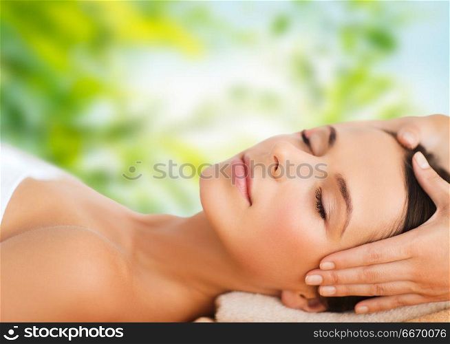 wellness, spa and beauty concept - close up of beautiful woman having face massage over green natural background. close up of beautiful woman having face massage. close up of beautiful woman having face massage