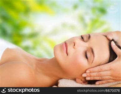 wellness, spa and beauty concept - close up of beautiful woman having face massage over green natural background. close up of beautiful woman having face massage. close up of beautiful woman having face massage