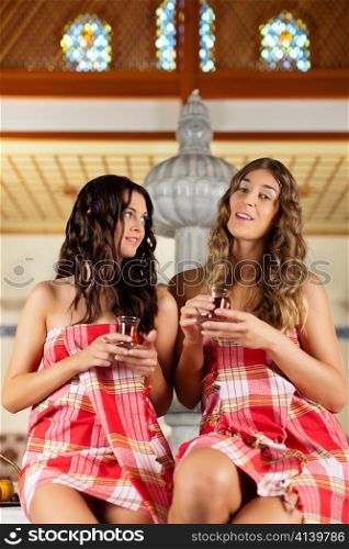 Wellness - two women, presumably they are friends, are relaxing in relaxation room with tea
