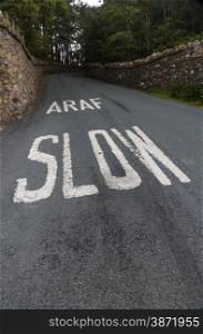 Welsh lane with white written Araf, Slow bilingual in Welsh and English. Wales, United Kingdom.