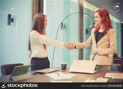 Western business women shaking hands in a meeting room, Multi et. Western business women shaking hands in a meeting room, Multi ethnic. Western business women shaking hands in a meeting room, Multi ethnic