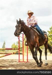 Western cowgirl woman training riding horse. Sport. Active western cowgirl woman training riding horse jumping over fence. Equestrian sport competition and activity.