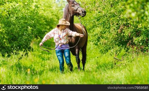 Western cowgirl woman with horse. Sport activity. Active western cowgirl woman in hat walking with horse. American girl in countryside ranch.