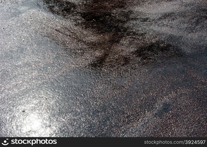 Wet asphalt background. Wet asphalt background with reflections of the sun during a day after heavy rain