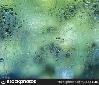 wet drops of water against glass pane with green background