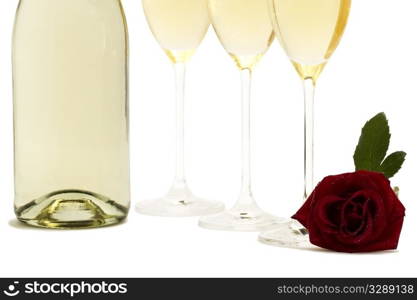 wet red rose in front the bottom from three champagne glasses and a champagne bottle. wet red rose in front the bottom from three champagne glasses and a champagne bottle on white background