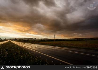 Wet road after rain and sunset over fields. Wet road and sky