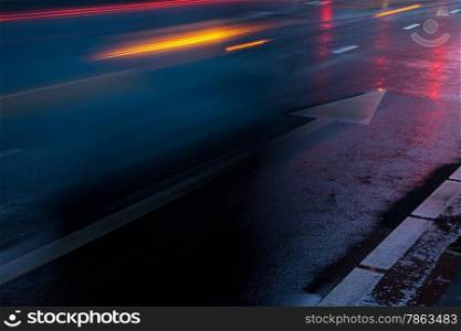 wet road with reflections of traffic lights and speeding cars
