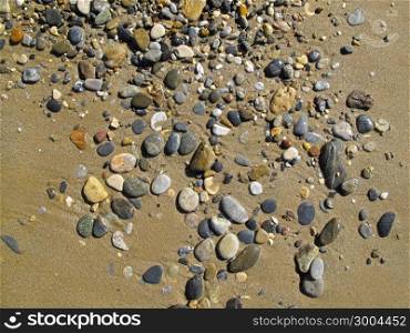 Wet sand background with sea pebbles