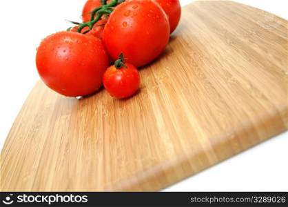 Wet Tomato. Close-up of large and small tomatoes with water droplets on a wooden cutting board