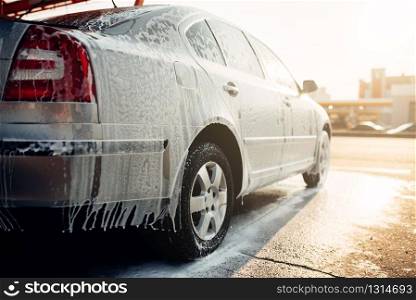 Wet vehicle in foam, automobile in suds, car wash. Carwash station. Wet vehicle in foam, automobile in suds, car wash
