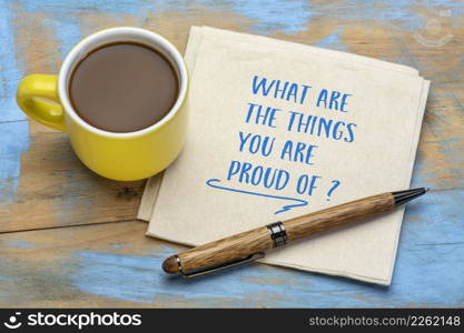 What are the things you are proud of? Handwriting on napkin with a cup of coffee. Reviewing achievements and accomplishments, personal development concept.