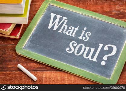 What is soul spiritual question on a slate blackboard with a white chalk and a stack of books against rustic wooden table