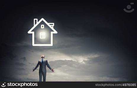 What is your dream house. Businessman with hands spread apart and house model above