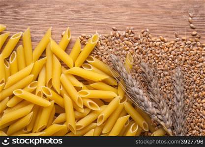 wheat and whole wheat penne rigate pasta closeup on background of the old wooden table