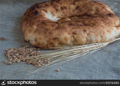 Wheat ears and pita bread with wheat grains lie on burlap