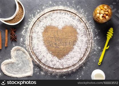 Wheat flour at wooden  bread cutting board with bakery ingredients for homemade baking on table. Food recipe cookies concept at stone background texture with copy space. Flat lay top view