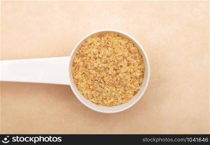 Wheat germs in measuring spoon on brown background