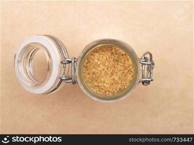 Wheat germs in open jar on brown background