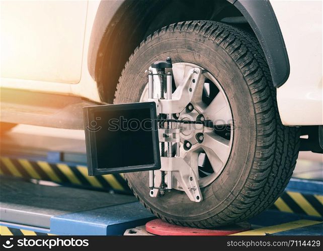 Wheel alignment equipment car mechanic installing sensor suspension adjustment auto sets on tire for diagnostics in the garage car service and repair