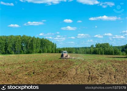 Wheel tractor working in the field in Sunny summer day.