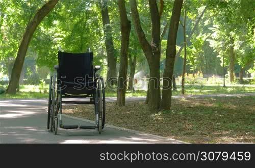 Wheelchair left empty outdoors in park in summer.