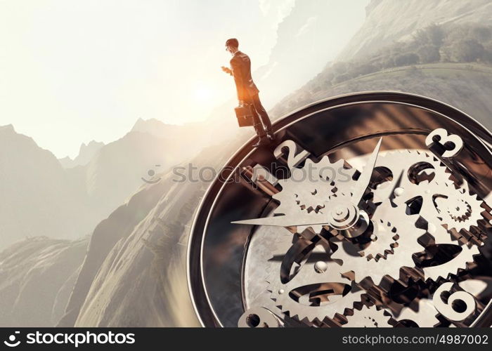 When time is passing. Businessman standing on old clock mechanism against sky background