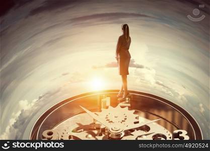 When time is passing. Businesswoman standing on old clock mechanism against sky background