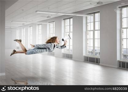 When tired of monotonous work. Young careless businesswoman flying in modern office interior