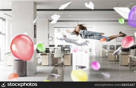 When tired of monotonous work. Young careless businesswoman flying in modern office interior