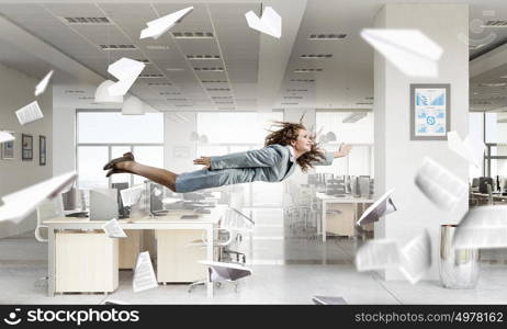 When tired of monotonous work. Young careless businesswoman flying in modern office interior