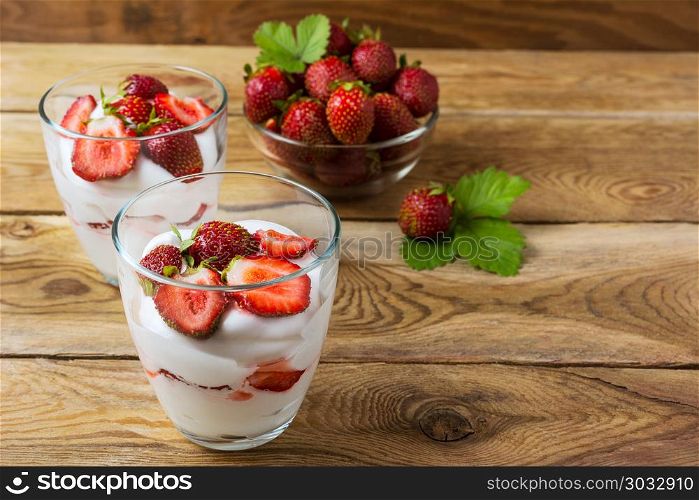 Whipped cream with strawberry on wooden background. Summer dessert with fresh ripe strawberry.. Whipped cream with strawberry on wooden background