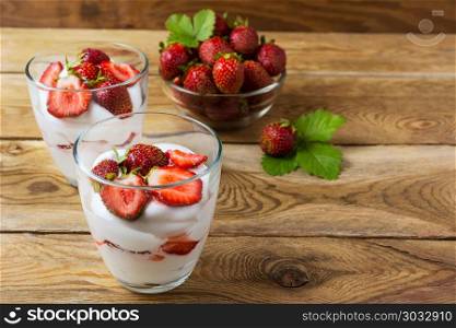 Whipped cream with strawberry on wooden background. Summer dessert with fresh ripe strawberry.. Whipped cream with strawberry on wooden background